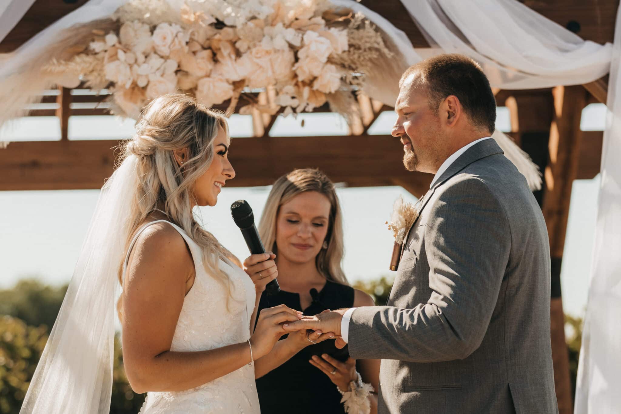 Bride and groom exchanging rings at outdoor wedding.