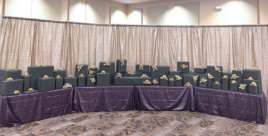 Black gift boxes with gold bows on tables