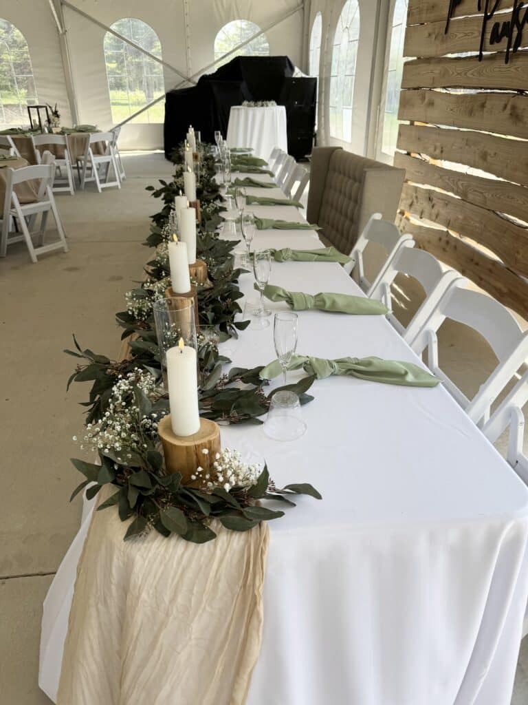 Rustic wedding head table with greenery and candles