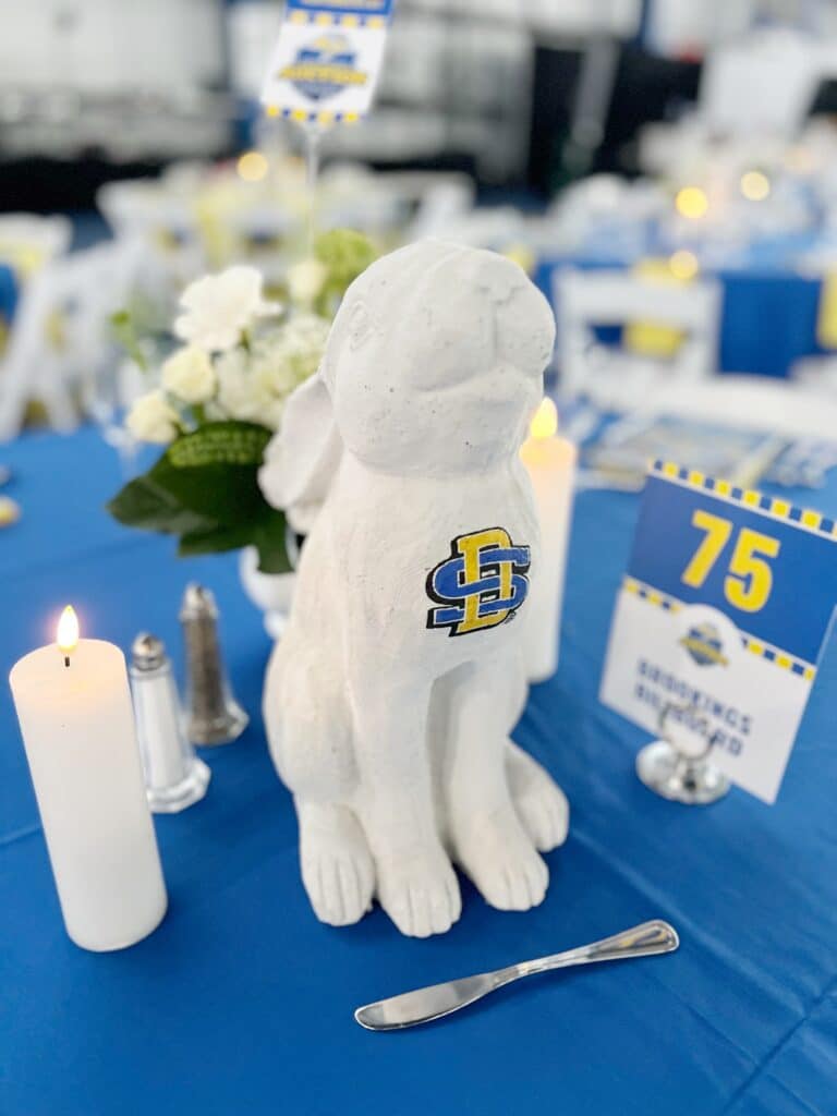 White dog statue with blue-yellow logo on table