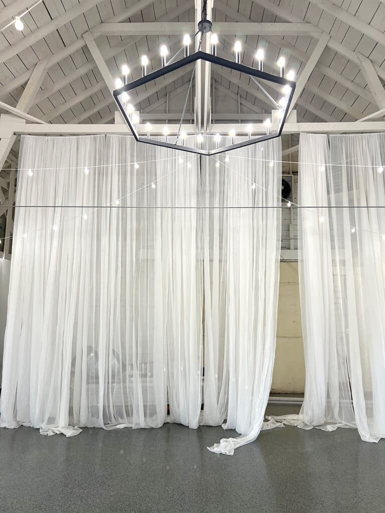 White sheer curtains under modern chandelier