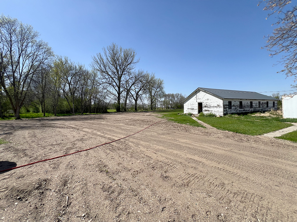 Old white barn beside large dirt lot