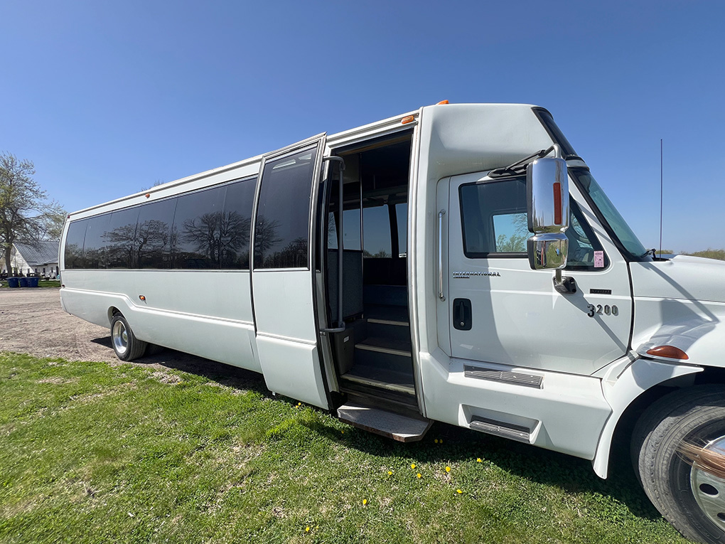White shuttle bus parked on grass with open door