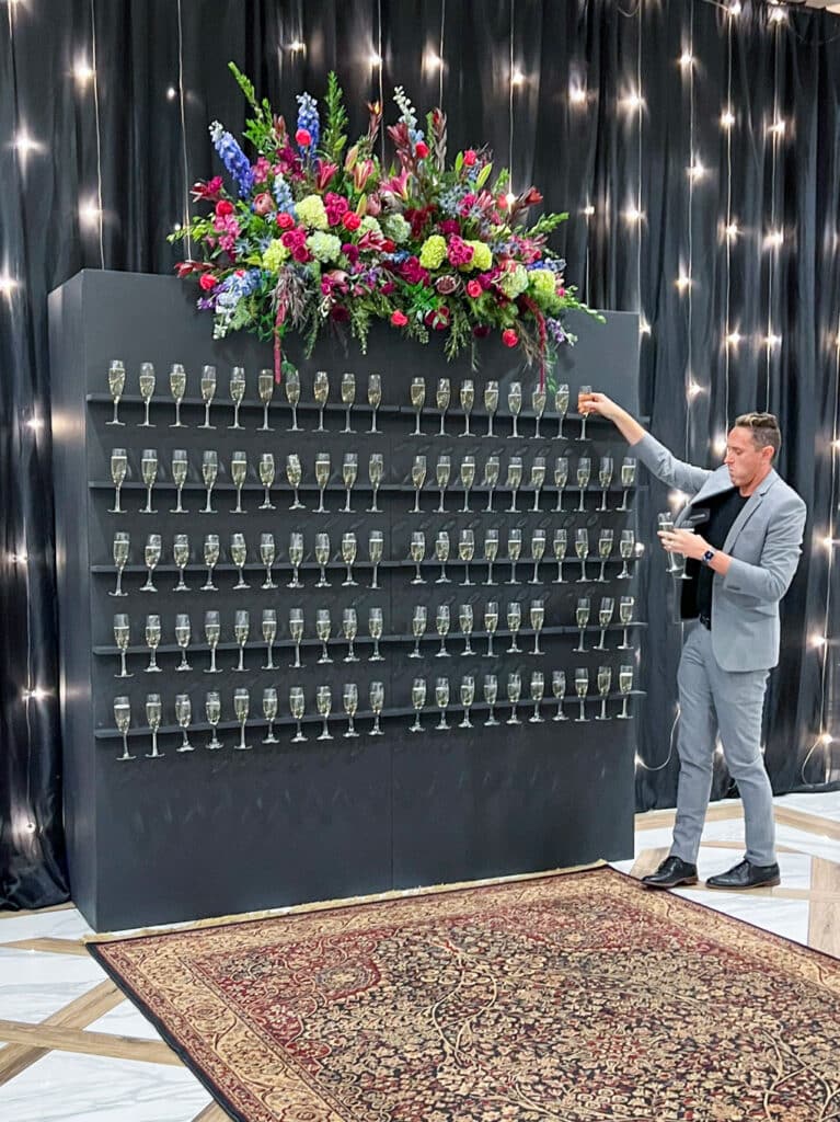 Man arranging champagne glasses on display wall