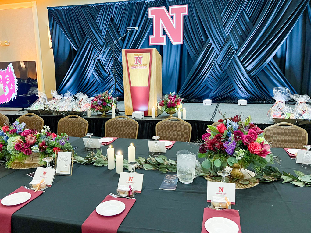 Decorated banquet hall with podium and floral centerpieces