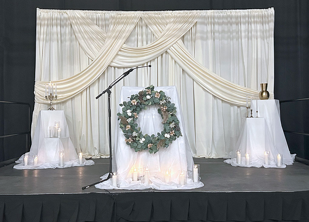 White draped stage with wreath and candles