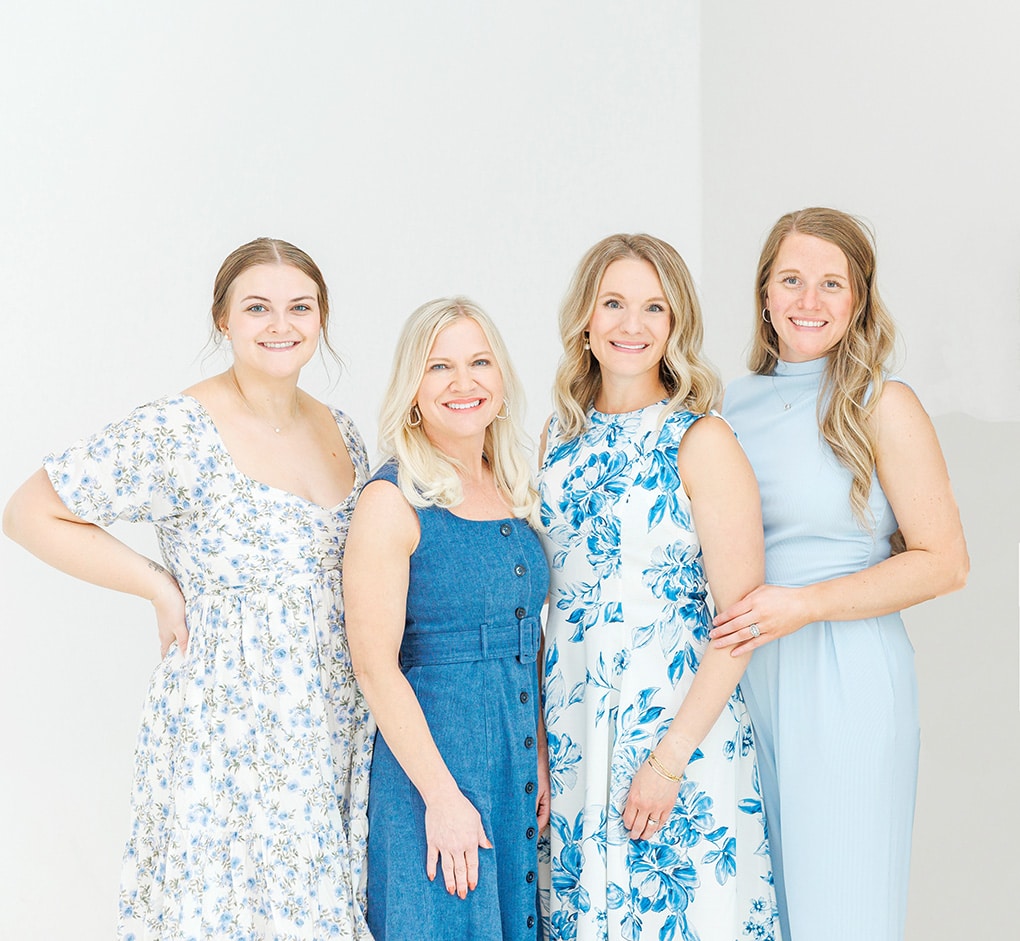 Four women smiling in blue dresses