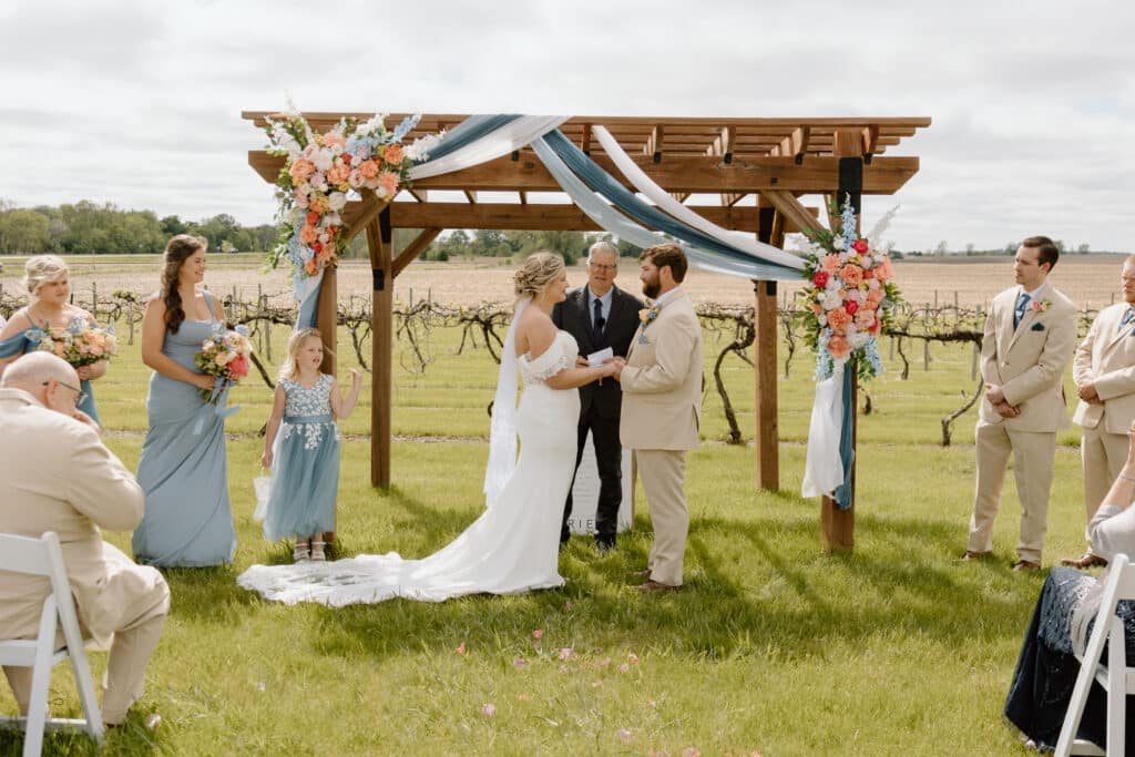 Wedding party beneath flower-draped wooden pergola