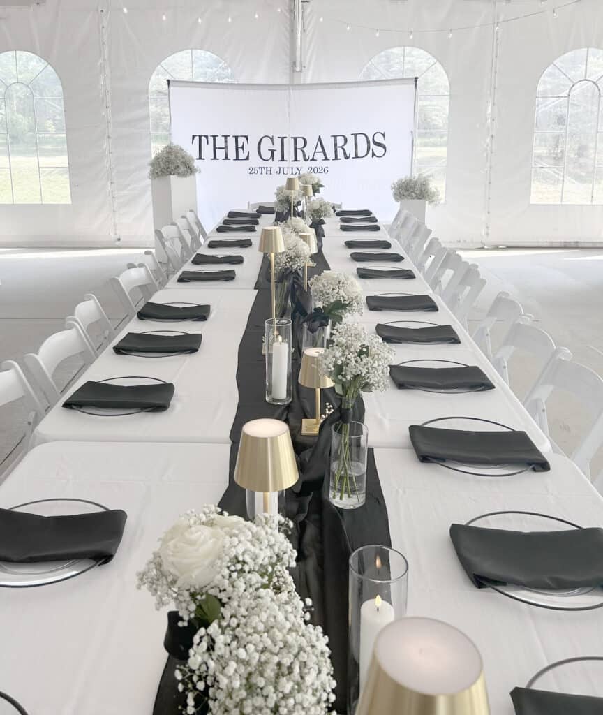 Elegant black-and-white wedding reception tables inside a white tent.