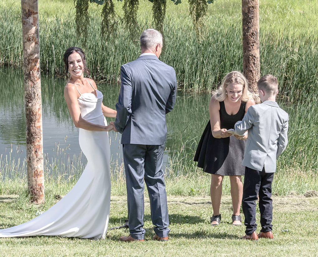 Bride and groom with children at lakeside wedding