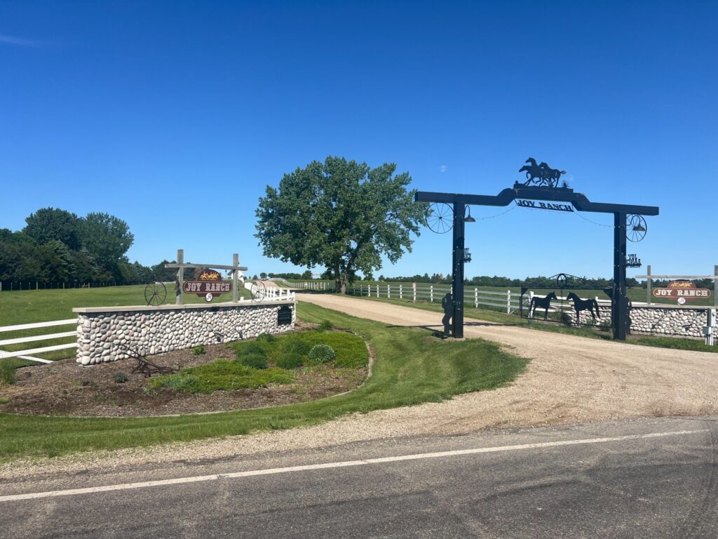 Joy Ranch entrance with horse silhouettes and white fences