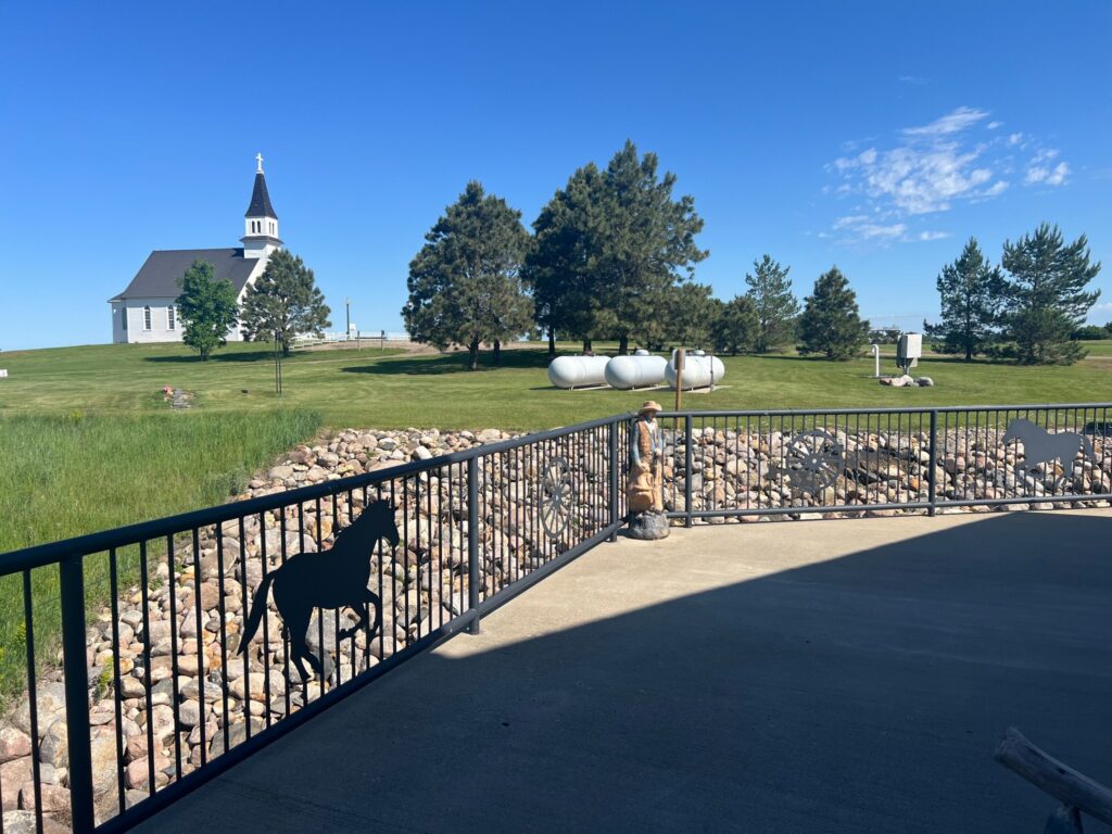 White church beside ranch-themed railing under blue sky