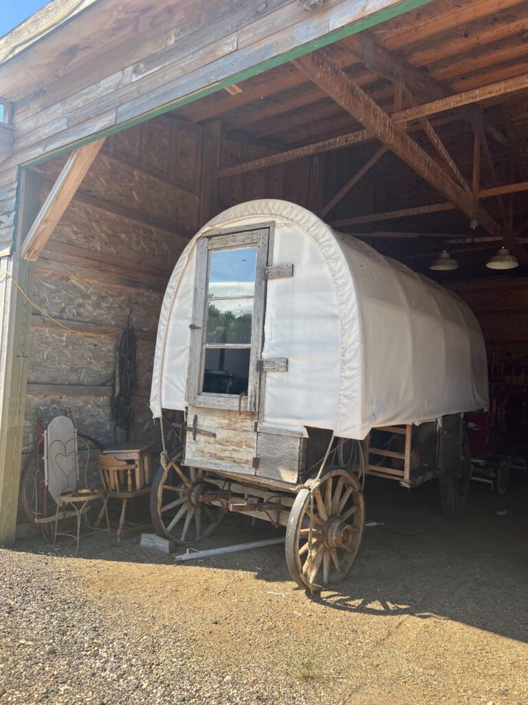 Vintage covered wagon stored inside a rustic wooden barn