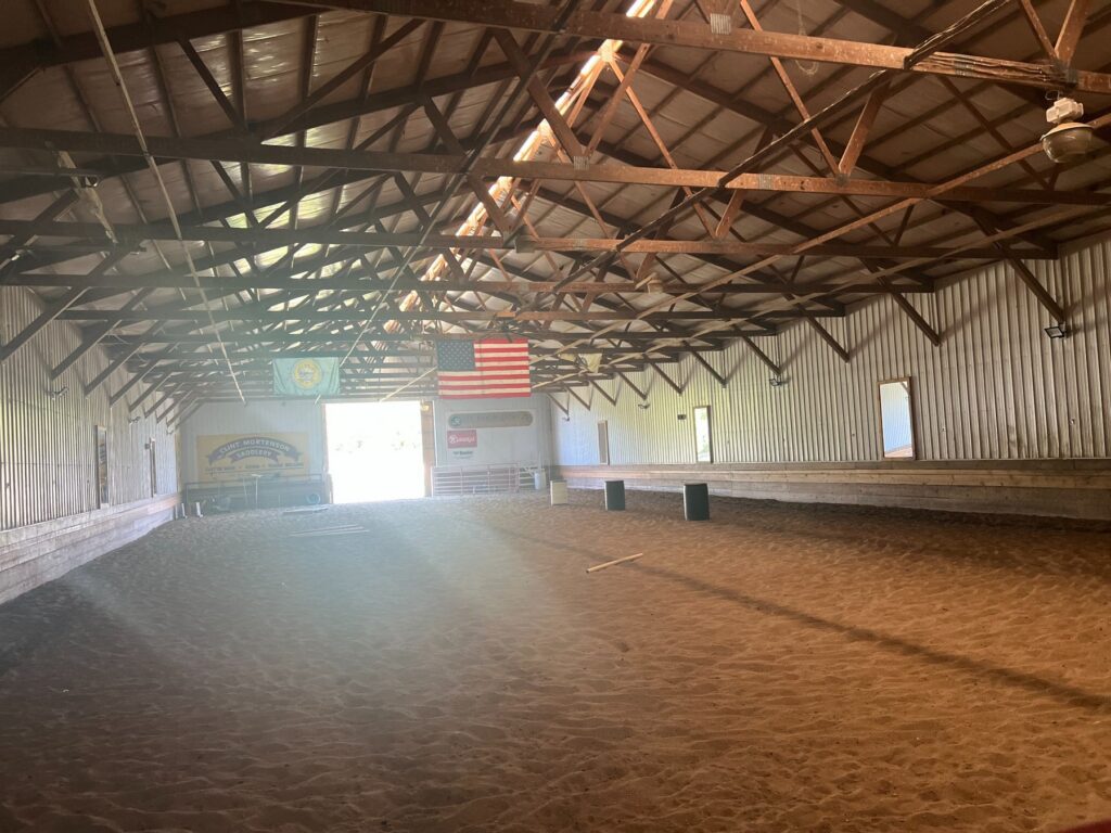Indoor riding arena with sandy floor and American flag