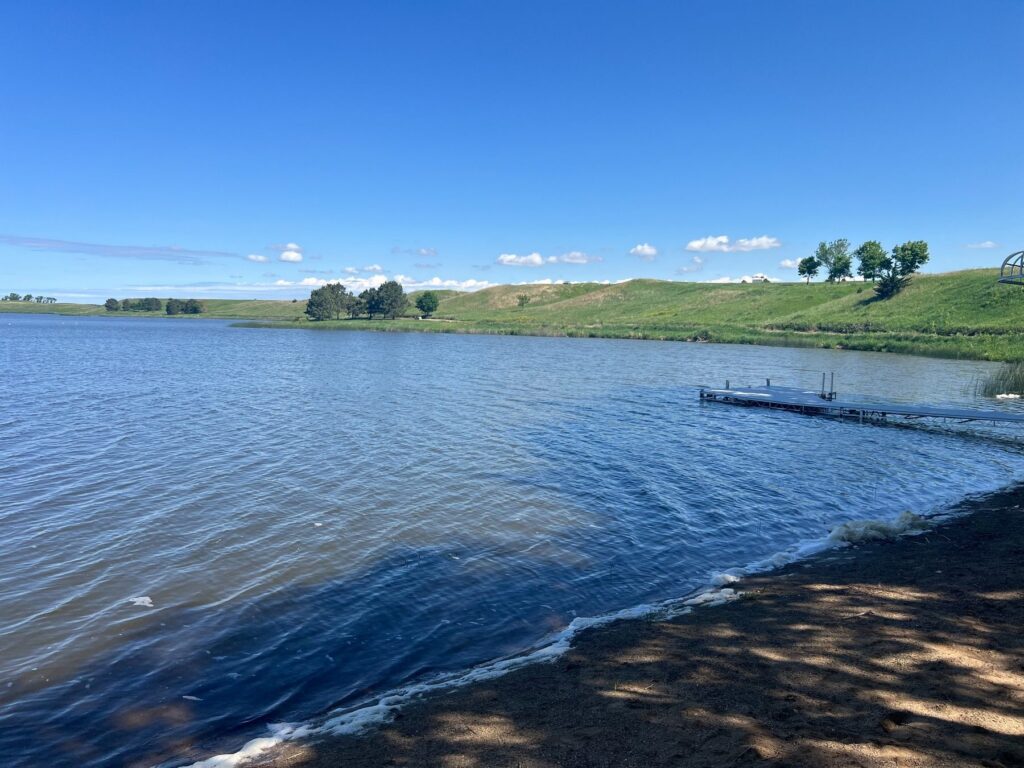Calm lake with dock and green hills