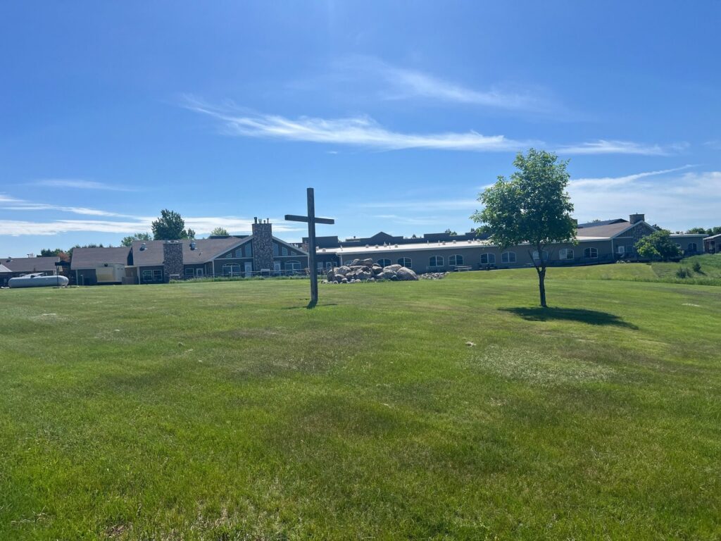 Wooden cross on lawn before large building