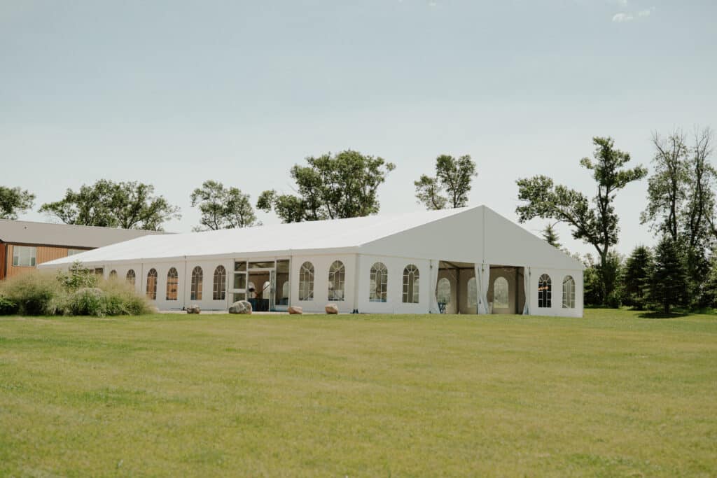 White event tent beside trees on a sunny lawn