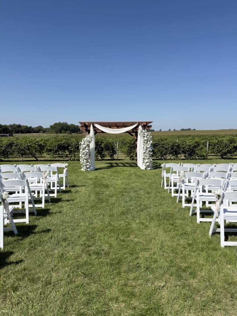 Outdoor wedding arbor and white chairs in a vineyard