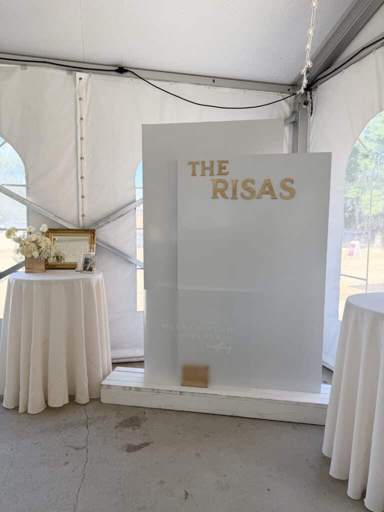 White wedding reception space with floral table and personalized sign