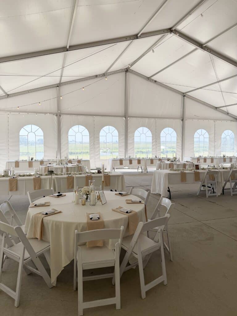 Elegant white wedding reception inside a windowed event tent