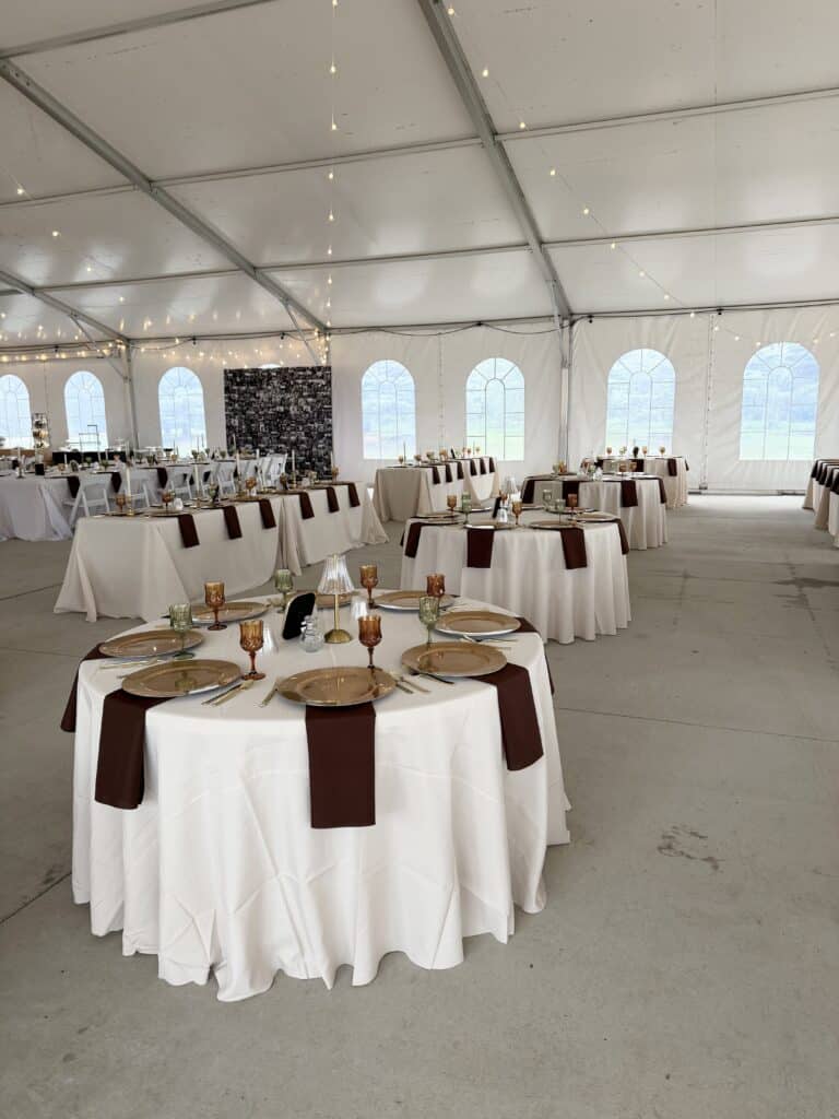 Elegant banquet tables set inside a white event tent