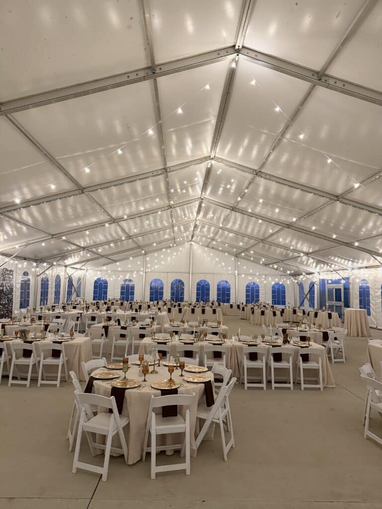 Elegant banquet tables beneath string lights in a white tent