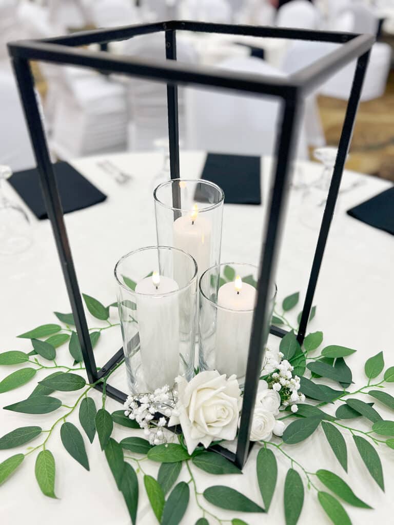 Black lantern centerpiece with candles, roses, and greenery