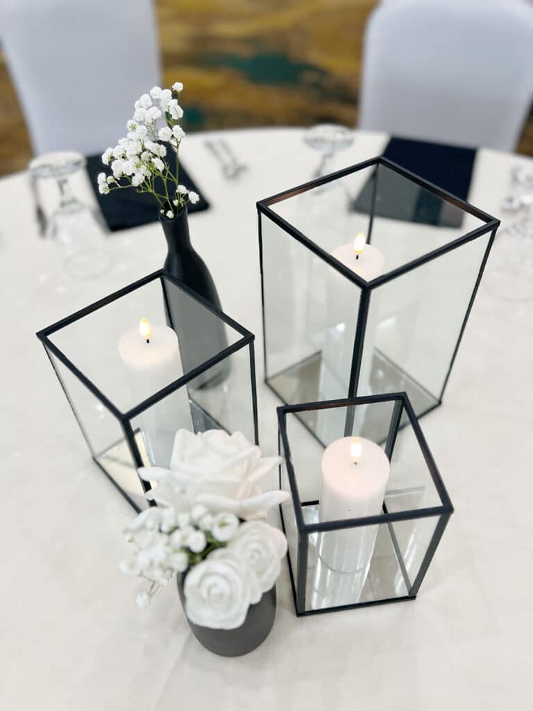 Black glass lanterns and white flowers on table
