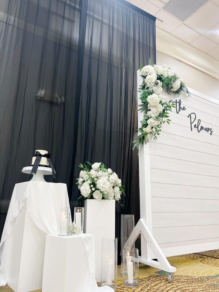 White floral memorial display with candles and black drapery