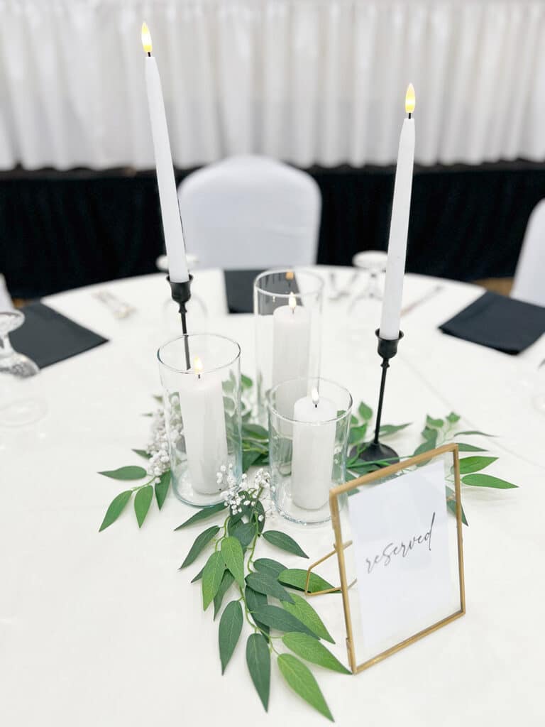 Elegant candle centerpiece with greenery and reserved sign