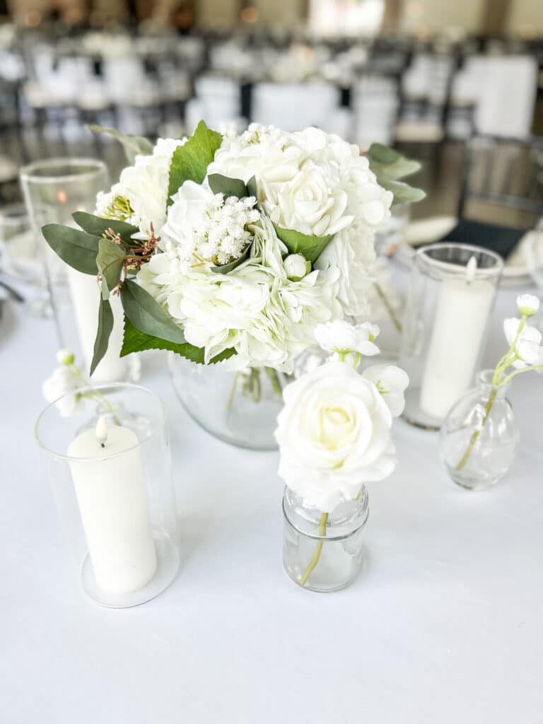 White floral centerpiece with candles on an elegant table