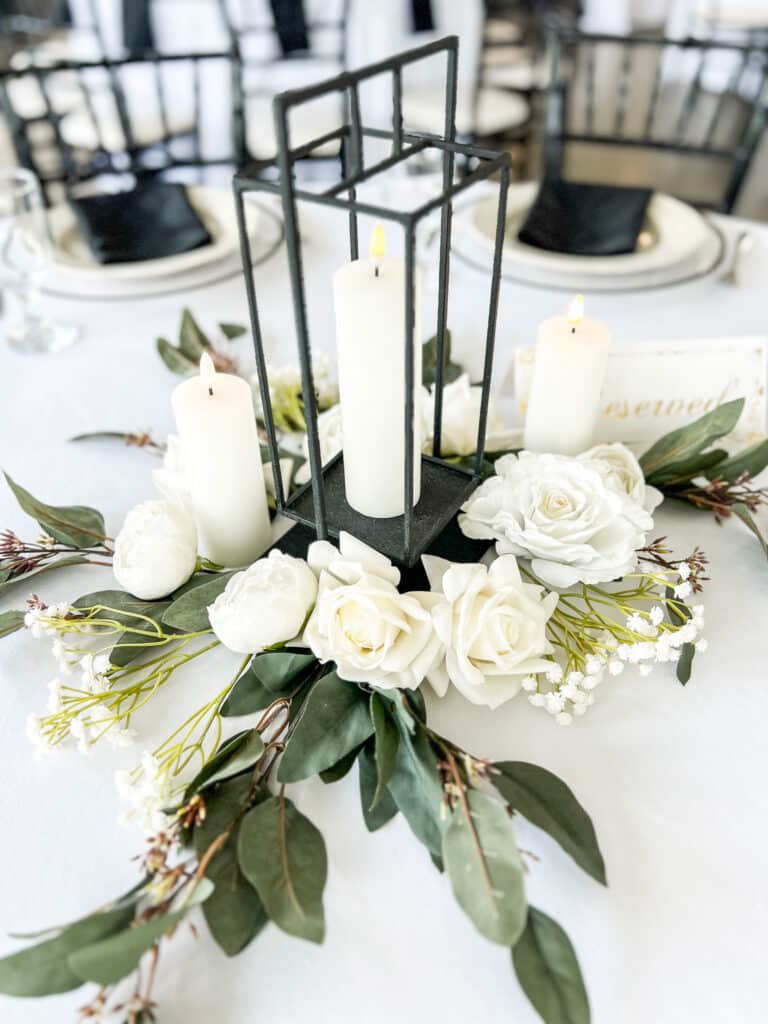 White floral centerpiece with candles in black lantern