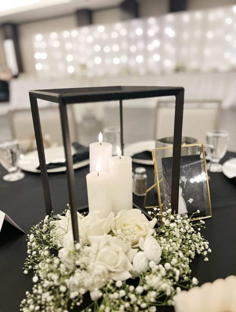 White candles and roses beneath black lantern at formal table