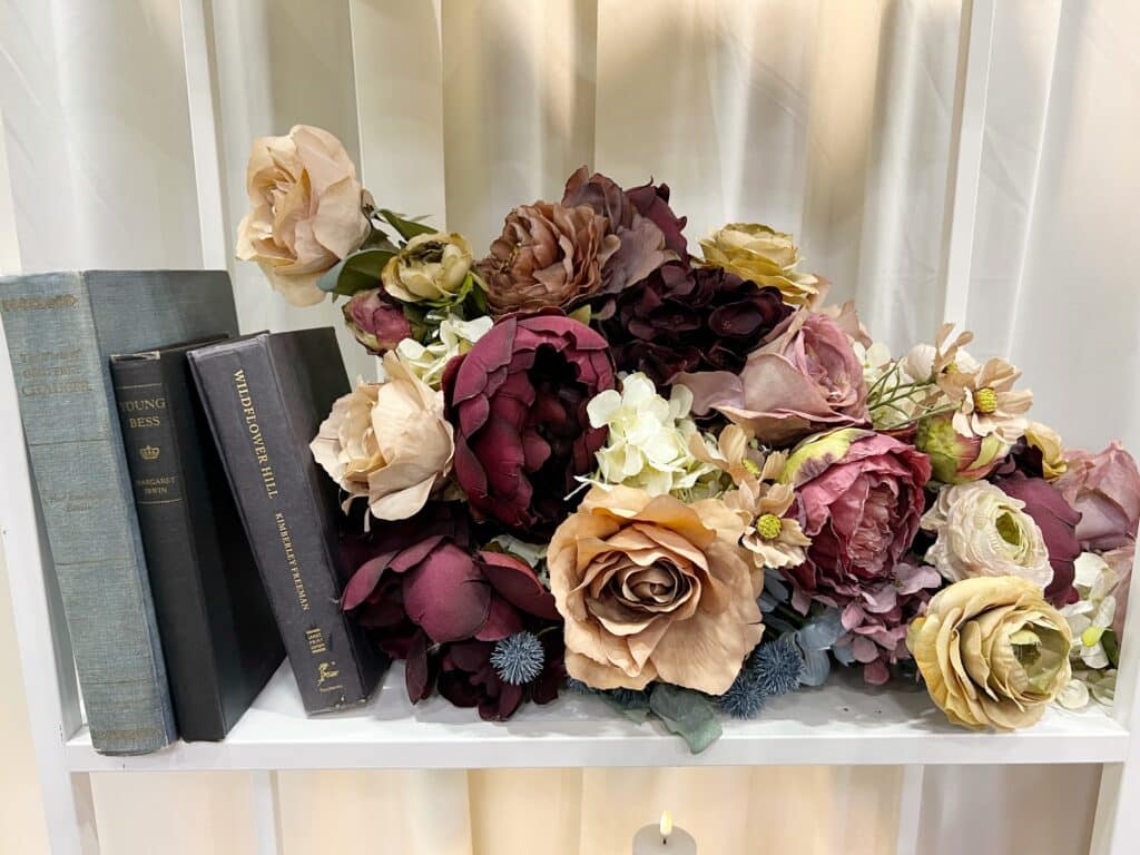 Vintage books nestled among burgundy and cream flowers