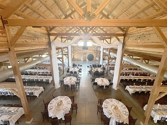 Rustic barn wedding reception with round tables and draped fabric