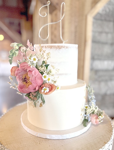 Two-tier white wedding cake with pink floral arrangement