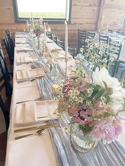 Pastel floral centerpiece on elegantly set rustic dining table