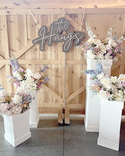 Rustic wedding floral display with “the Hangs” sign