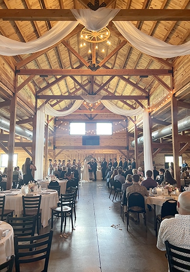 Rustic barn wedding reception with guests and draped lights