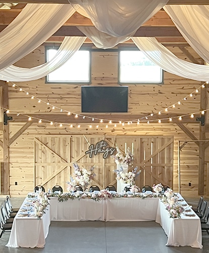 Rustic barn wedding reception with draped fabric and floral tables