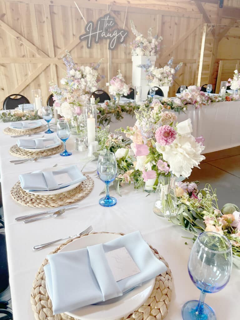 Floral barn wedding reception table with blue glassware