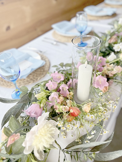 Floral tablescape with candle and blue-rimmed glassware