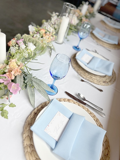 Elegant table setting with blue napkins, flowers, and glassware