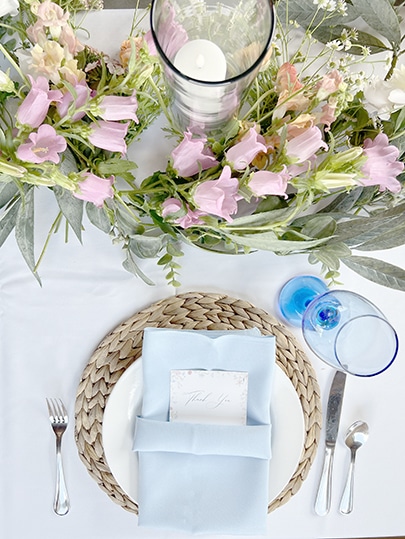 Elegant pastel floral tablescape with blue napkin and glassware