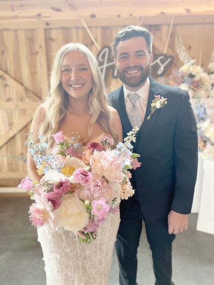 Smiling bride and groom pose with colorful wedding bouquet