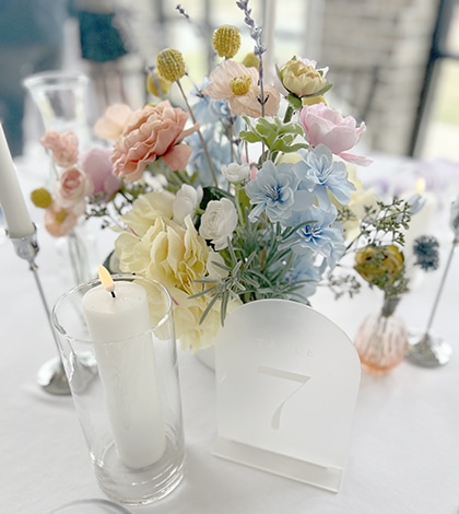 Pastel floral centerpiece with candle and table number seven
