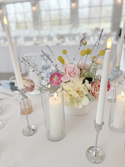 Pastel floral centerpiece with lit white taper candles