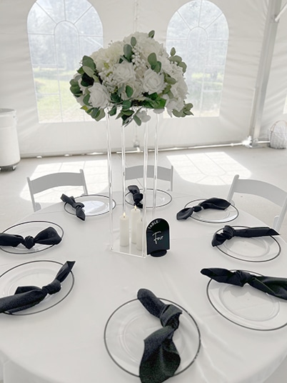 Elegant white wedding table with floral centerpiece and black napkins
