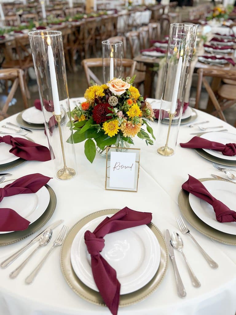 Elegant banquet table with candles, floral centerpiece, and burgundy napkins