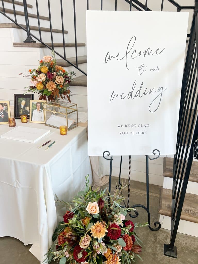 Wedding welcome sign beside floral guest book table